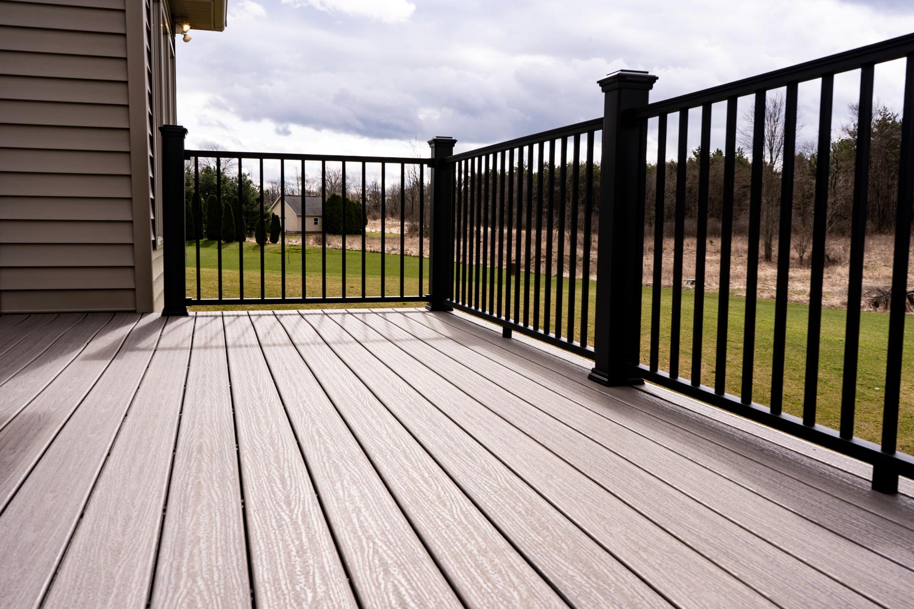 Brown backyard deck with black railing