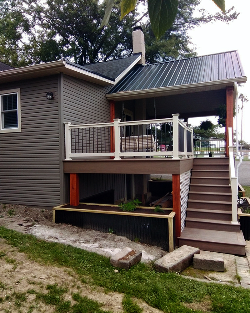 Backyard deck with black railing and staircase on tan vinyl-sided house