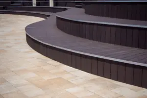Curved multi-level deck with dark decking boards next to a light stone patio