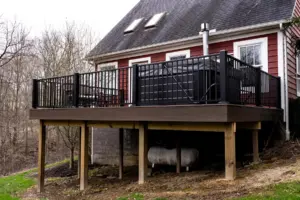 Raised deck with black railing overlooking a wooded backyard